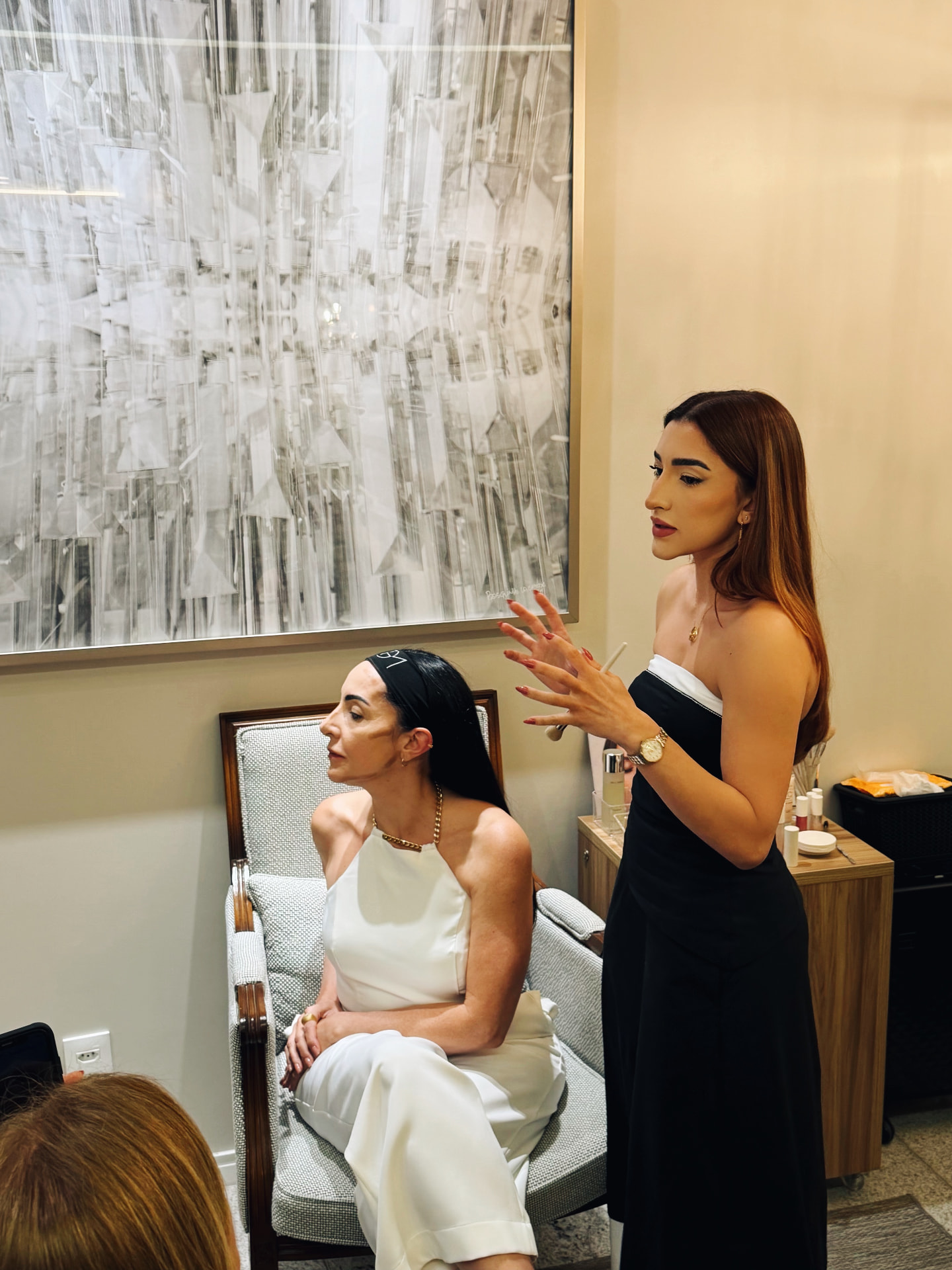 Instrutora demonstrando maquiagem com pincel em uma cliente sentada, durante workshop da MGM